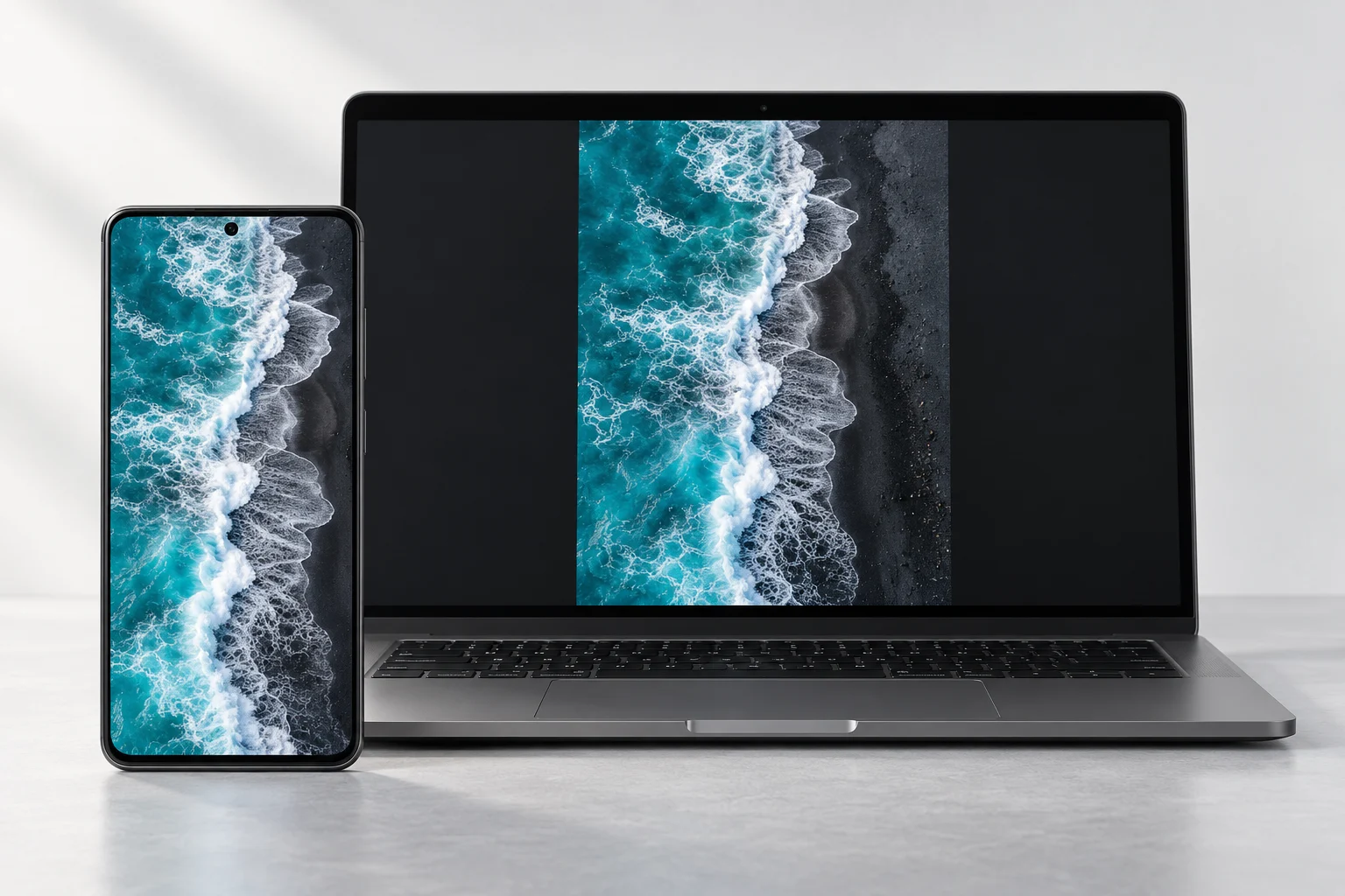 A phone and laptop showing the same turquoise ocean waves, illustrating screen sharing